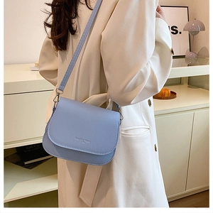 Détail de la sacoche en cuir mat bleu clair portée par un mannequin dans un intérieur