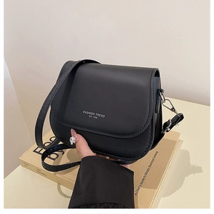 Detail of black matte leather saddle bag showing fashion trend print and stitching