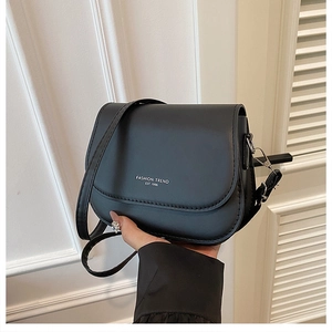 Detail of black saddle crossbody bag with Fashion Trend logo and adjustable leather strap