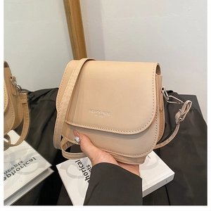 Close-up of beige leather crossbody bag with Fashion Trend EST 1998 print and silver hardware