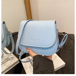Detail of light blue saddle bag with adjustable strap and fashion trend lettering