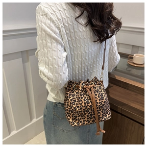 Model wearing leopard print bucket bag with drawstring closure and slim shoulder strap