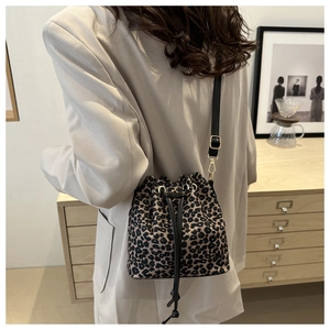 Leopard print bucket bag with drawstring closure and adjustable strap in lifestyle setting