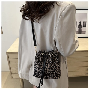 Detail of leopard print bucket bag featuring black drawstring closure and gold hardware