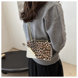 Close-up of leopard print shoulder bag with gold chain strap on grey knit sweater