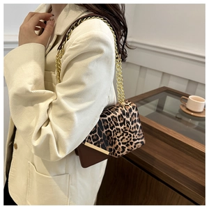 Detail of leopard print flap bag with gold chain strap on beige corduroy blazer