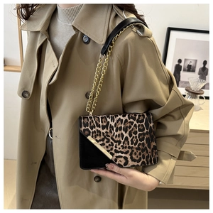 Detail of leopard print flap bag with gold hardware on a chic beige trench coat