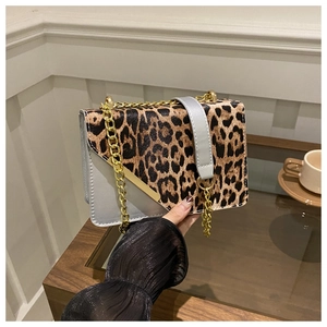 Detail of trendy crossbody bag with leopard print flap and gold chain strap accent
