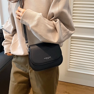 Minimalist black PU leather saddle bag with white lettering and adjustable shoulder strap