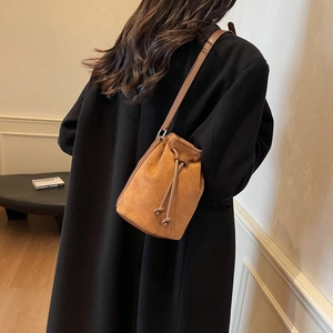 Brown frosted leather bucket bag with drawstring closure and slim shoulder strap on model
