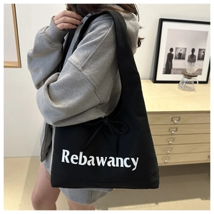 Detail of black canvas tote bag with Rebawancy lettering and side bow ribbon decoration
