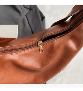 Close-up of smooth gold metal zipper and premium brown leather texture on hobo bag