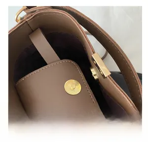 Dettaglio della borsa a secchiello in pelle marrone con chiusura magnetica e interno viola