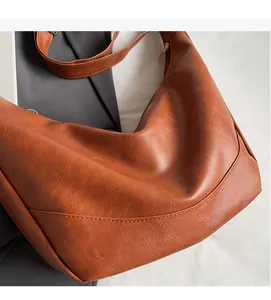 Close-up of caramel brown tote bag showing textured PU leather and long shoulder strap
