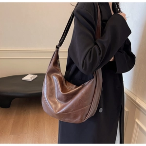 Detail of dark brown leather hobo bag showing retro texture and soft shoulder strap
