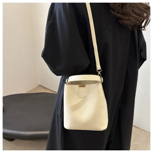 Detail einer beige Leder-Beuteltasche mit Tragegriff und goldfarbenem Modeschriftzug