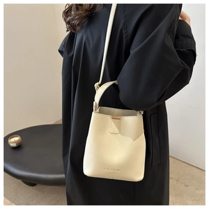 Dettaglio borsa a secchiello in pelle beige con chiusura dorata e scritta fashion