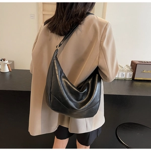 Detailed view of the black pleated crescent tote bag worn with a casual beige blazer