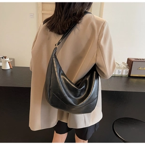 Chic black leather hobo bag with moon shape and spacious design worn by a model