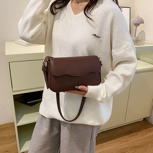 Borsa a tracolla in pelle marrone con patta a onde indossata da una modella in stile casual