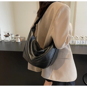 Detail of black pleated tote bag showing supple PU leather texture and shoulder drape