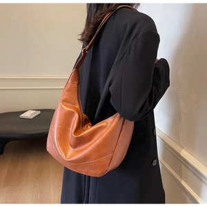 Side view of caramel leather hobo bag on black blazer with soft natural light