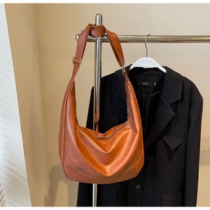 Close-up of a retro caramel hobo bag with smooth texture and golden metal buckle details