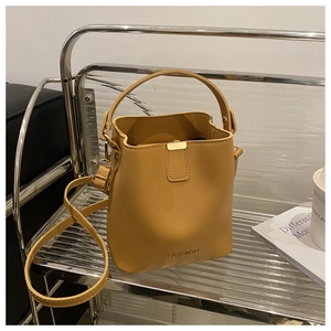 Detail der gelben Beuteltasche mit FASHION-Schriftzug und goldener Metallschließe