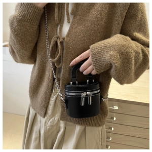 Close-up of black cylinder bucket bag with contrast stitching and silver chain strap