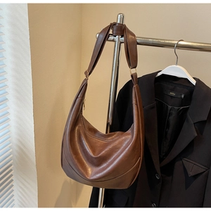 Close-up of a retro brown pleated tote bag hanging with a smooth gold metal zipper