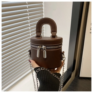 Detail of a dark brown mini cylinder bag showing white stitching and silver hardware