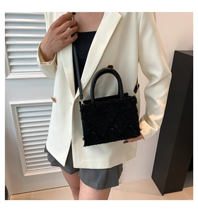Detailansicht der schwarzen gesteppten Umhängetasche an einem Model im weißen Blazer