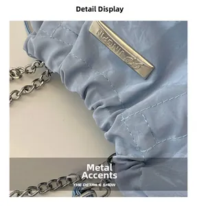 Details der hellblauen Kordelzugtasche mit glänzendem Faltenstoff und silberner Logoplakette