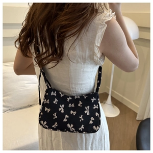Lifestyle view of the black bow-print canvas tote bag worn as a shoulder bag