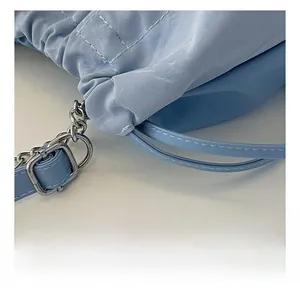 Detail einer hellblauen Kordelzug-Beuteltasche mit silberner Metallkette und Hardware