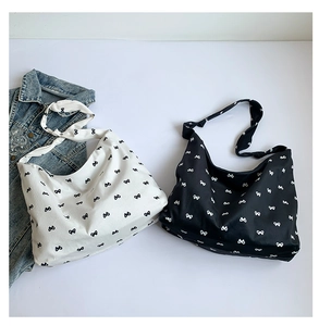 Detail of hobo tote bags with bow prints and knotted shoulder straps in black and white
