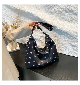 Detail of black nylon tote bag featuring white bow prints and wide shoulder strap