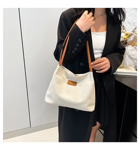 Gros plan sur un cabas en toile beige avec anses en cuir marron et étiquette de marque
