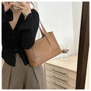 Detailansicht der braunen Leder-Eimertasche mit goldenen Nieten für lässigen Stil