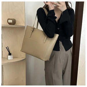 Detail of cross-stitch seams and smooth leather texture on large beige tote bag