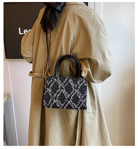 Detail of blue denim crossbody bag with white quilted fringe on a trench coat model