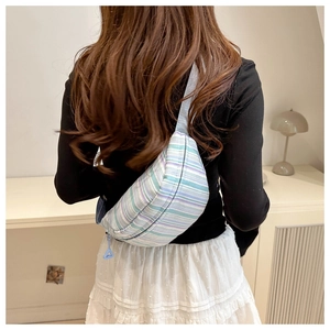 Detail of colorful striped nylon crossbody bag with blue adjustable strap and zipper pull
