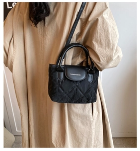 Close-up of black quilted bucket bag with white fashion lettering and crossbody strap