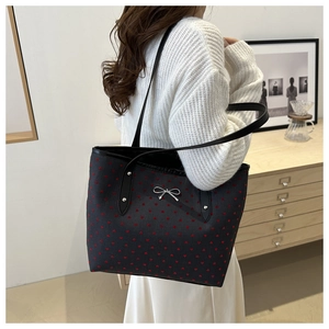 Close-up of black tote bag with red hearts and silver bow detail on shoulder