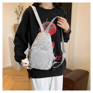 Détail du sac bandoulière argenté texturé avec pendentif en peluche blanche douce