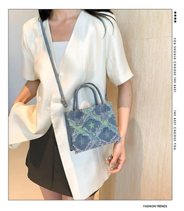 Detail of star pattern denim crossbody bag with distressed frayed edges on model