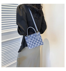Blue and white checkered denim crossbody bag with frayed edges shown on a model