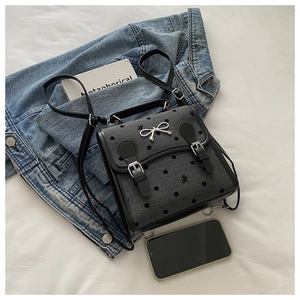 Detailansicht eines grauen Polka-Dot-Rucksacks mit silberner Schleife auf Denim