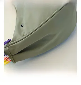 Close-up of olive green crossbody bag with textured fabric and rainbow woven strap