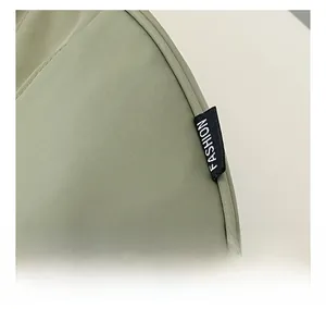 Detailed macro view of green fabric bag featuring a black FASHION label and neat stitching